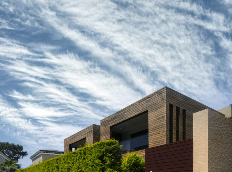 Modern houses with green plant wall on blue sky background. Actual eco architecture. Real estate concept