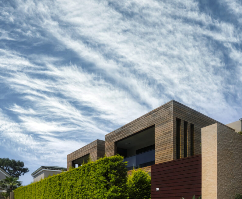 Modern houses with green plant wall on blue sky background. Actual eco architecture. Real estate concept
