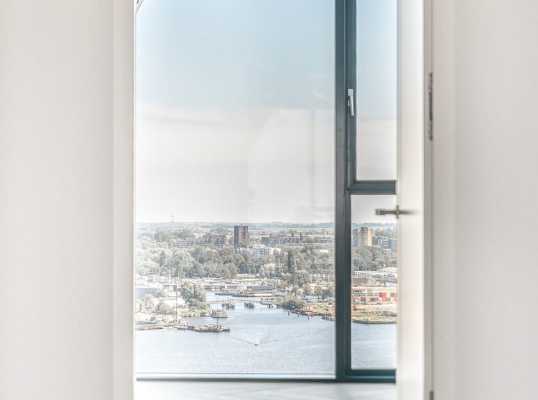 Doorway in apartment penthouse with wooden parquet flooring and wall windows viewing city