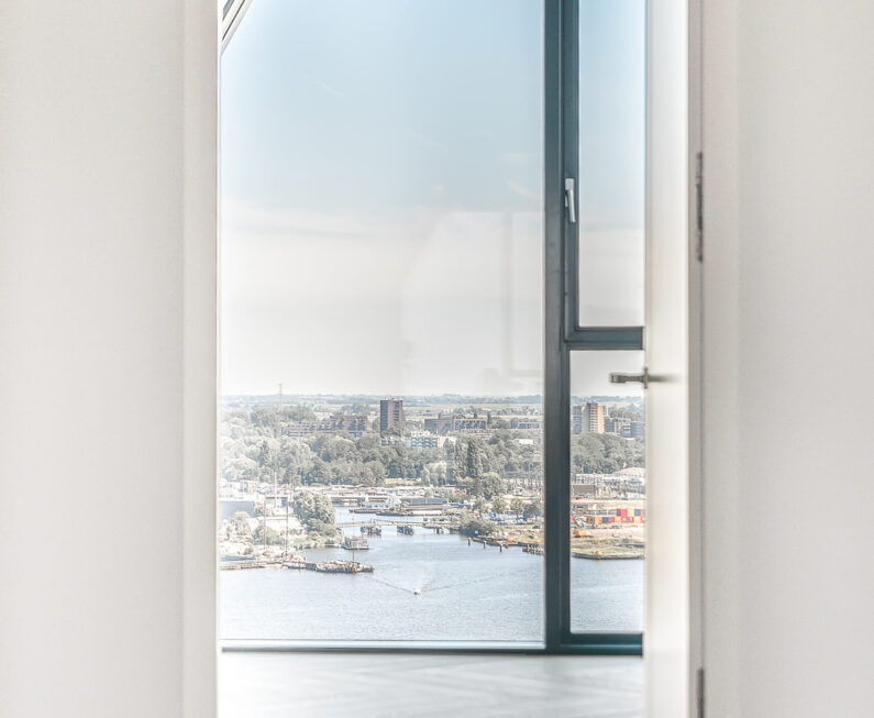 Doorway in apartment penthouse with wooden parquet flooring and wall windows viewing city
